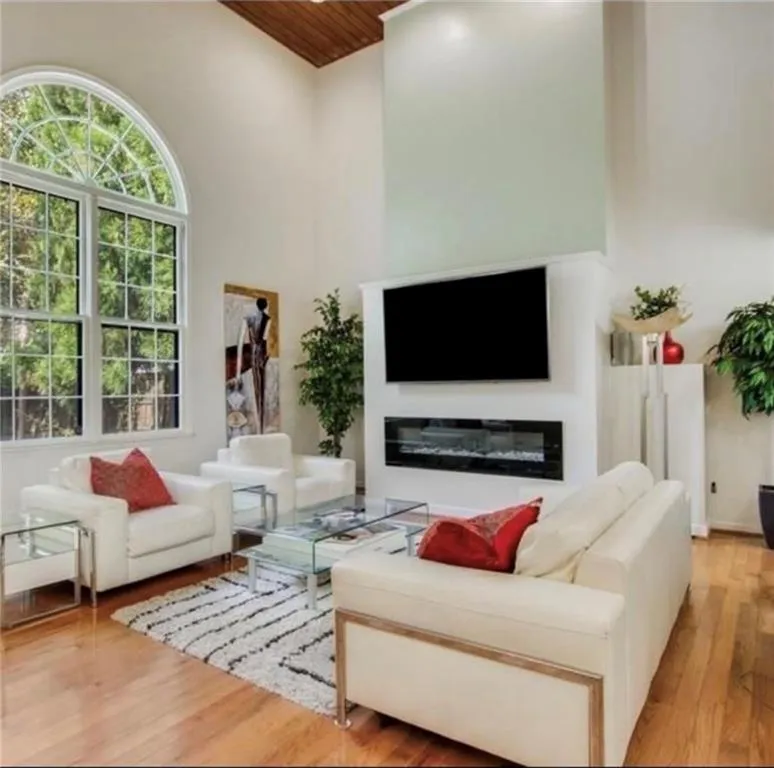 Living room with light wood-style floors, a high ceiling, and wood ceiling