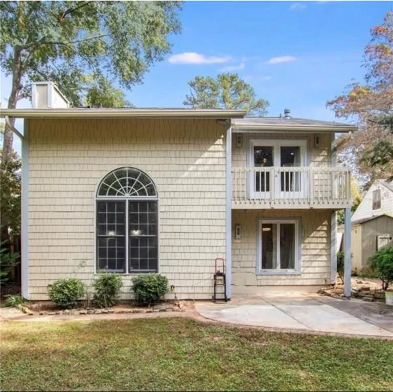 Back of property with a balcony, a yard, and a patio area