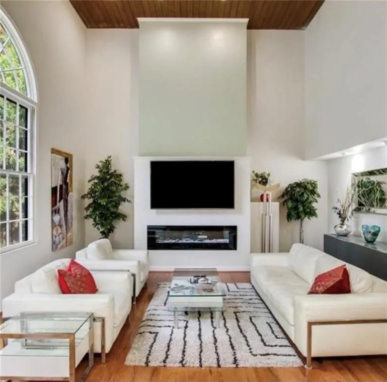 Living area with wood finished floors, wooden ceiling, a glass covered fireplace, and a high ceiling