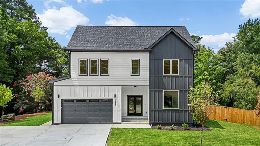 Modern two-story residence featuring a mixed-material exterior with board-and-batten siding and horizontal clapboard, complemented by a dark asphalt shingle roof