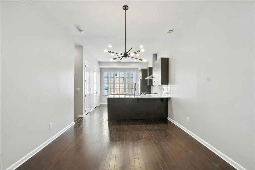Kitchen featuring light countertops, a chandelier, dark wood-type flooring, a peninsula, and a kitchen breakfast bar Kitchen featuring light countertops, a chandelier, dark wood-type flooring, a peninsula, and a kitchen breakfast bar