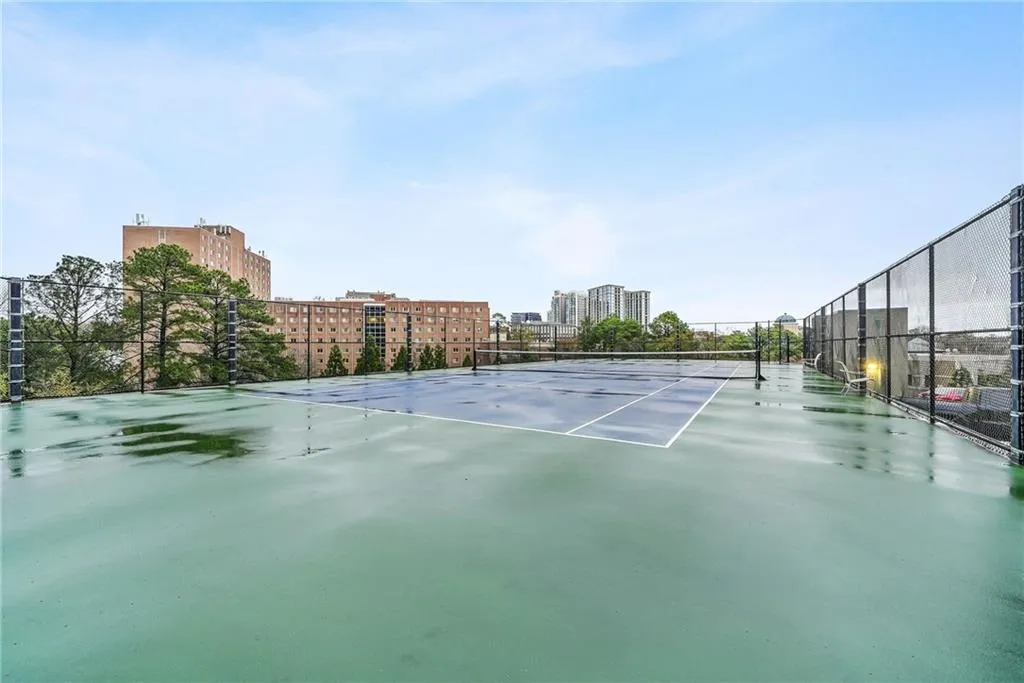 View of tennis court featuring a patio and a city view