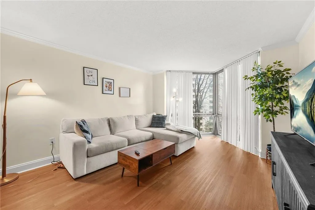 Living area with floor to ceiling windows, crown molding, light wood finished floors, and a textured ceiling