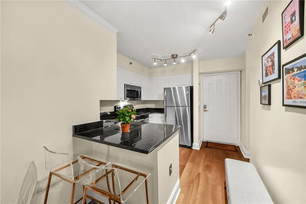 Kitchen with a kitchen bar, white cabinetry, stainless steel appliances, light wood-style floors, and a peninsula