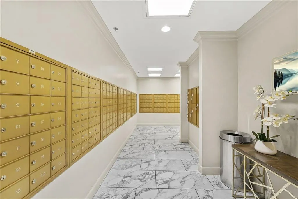 Corridor with mail area, light marble finish floors, ornamental molding, and recessed lighting
