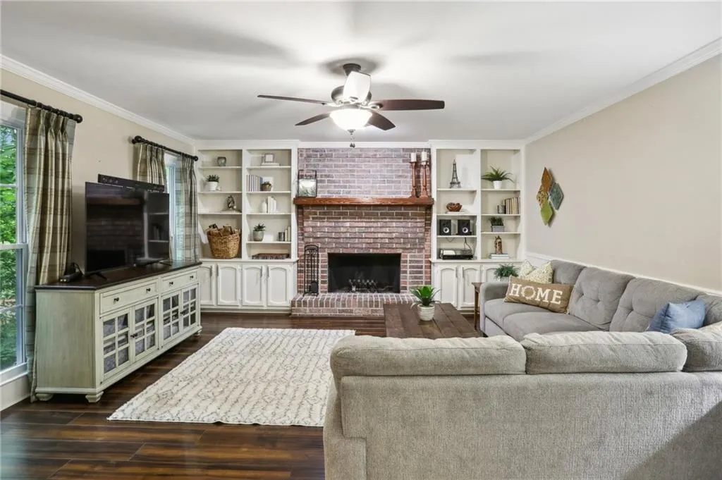 Living room featuring a wealth of natural light, a brick fireplace, ceiling fan, and dark hardwood / wood-style flooring