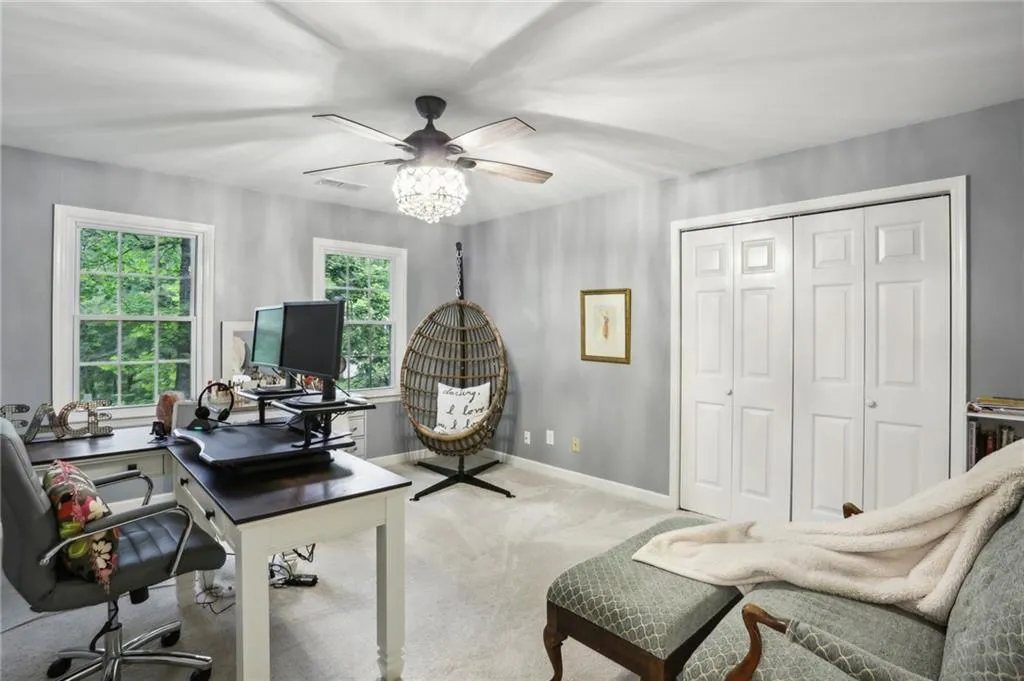 Home office with ceiling fan and light colored carpet