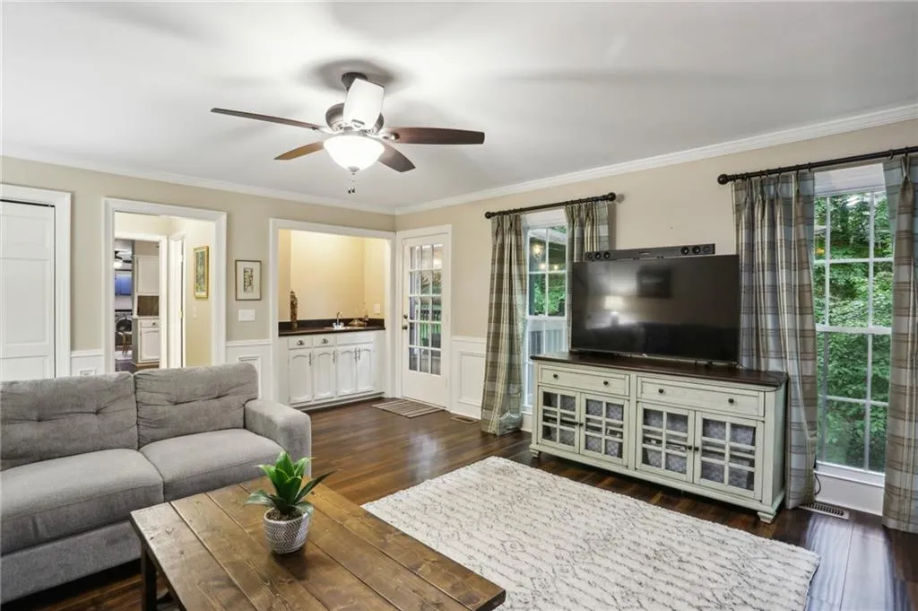 Living room with plenty of natural light, ornamental molding, ceiling fan, and dark hardwood / wood-style floors