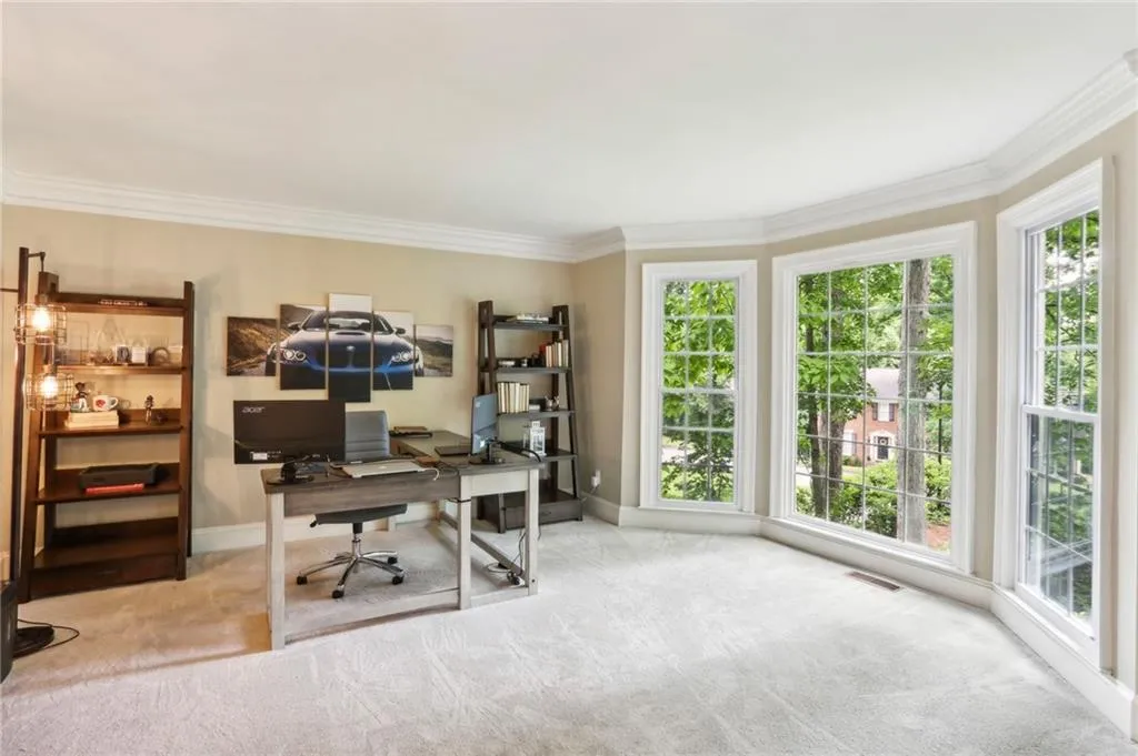 Carpeted office space with a healthy amount of sunlight and ornamental molding