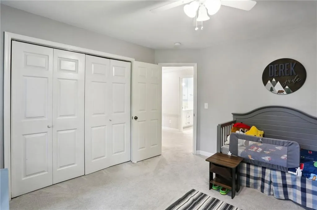 Bedroom with light carpet, a closet, and ceiling fan