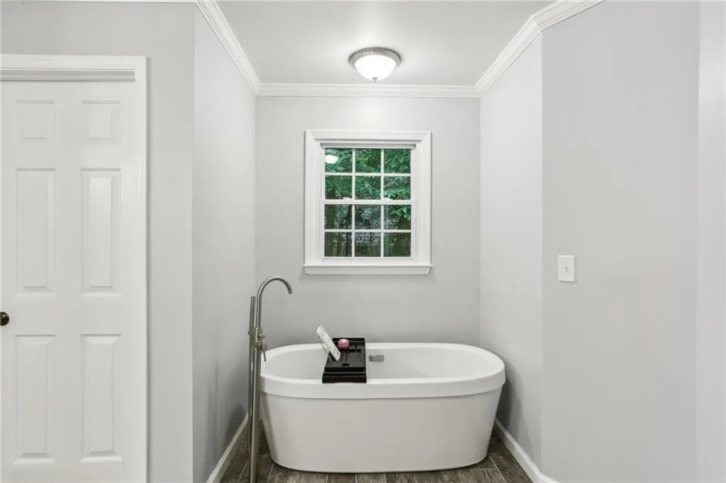 Bathroom with a bath, ornamental molding, and hardwood / wood-style floors