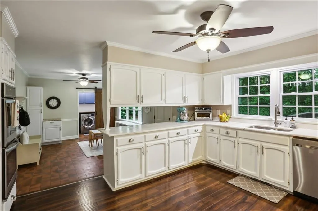 Kitchen with stainless steel appliances, washer / dryer, sink, and ceiling fan