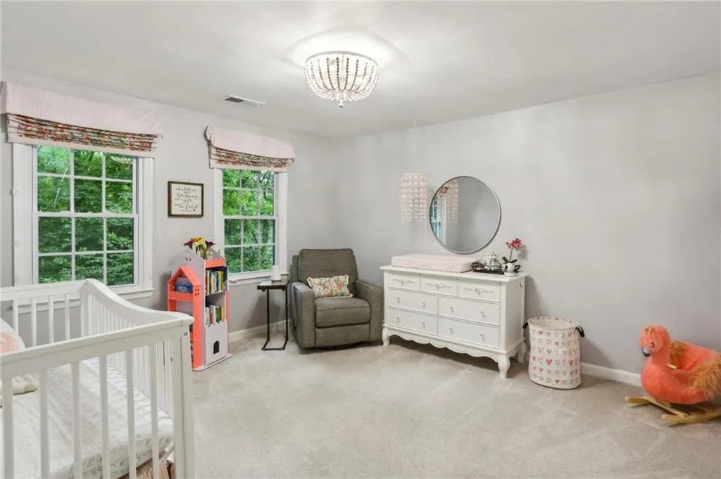 Carpeted bedroom featuring a notable chandelier and a nursery area