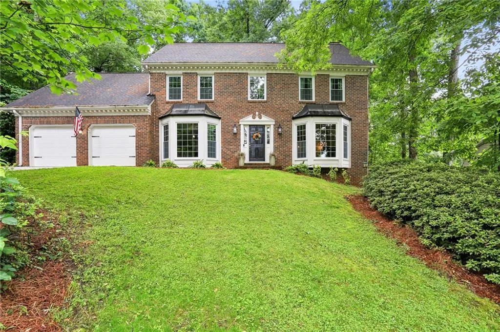 Colonial-style house featuring a garage and a front lawn