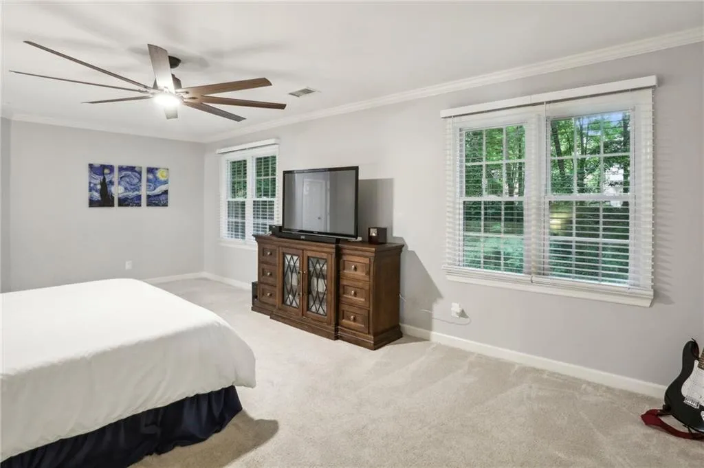 Bedroom with ornamental molding, ceiling fan, and carpet floors