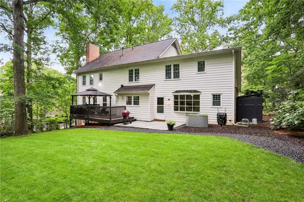 Rear view of property featuring a deck and a lawn