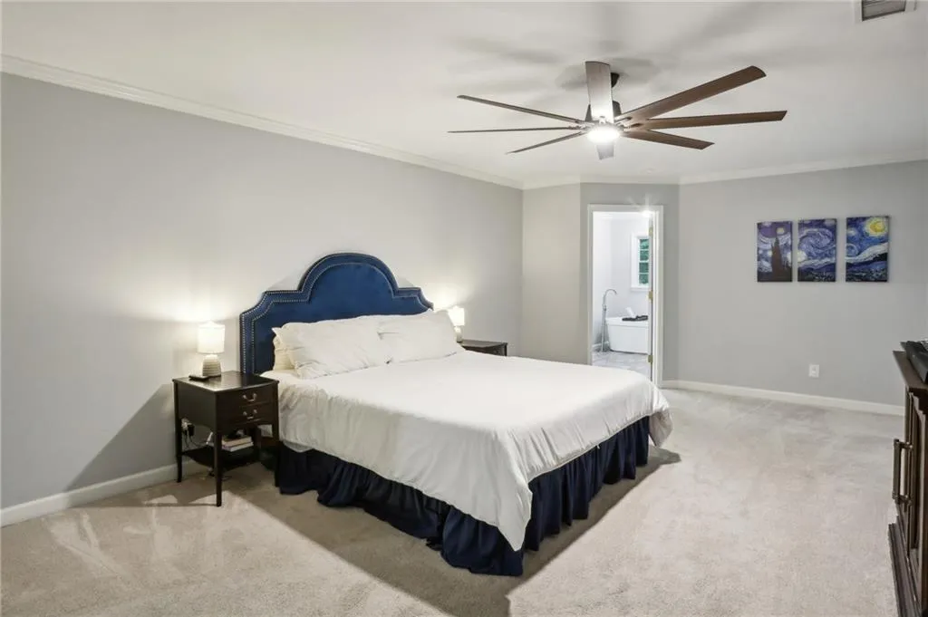 Bedroom featuring light colored carpet, ensuite bath, ceiling fan, and crown molding