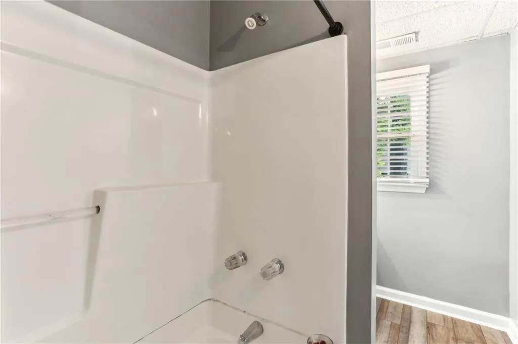 Bathroom with hardwood / wood-style flooring and shower / washtub combination