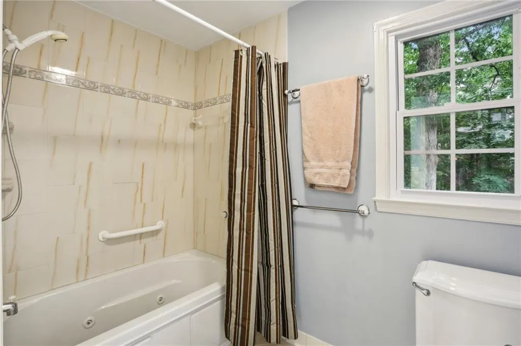 Bathroom featuring shower / bath combo with shower curtain, plenty of natural light, and toilet