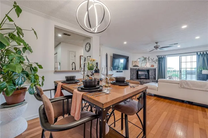 Hardwood flooring throughout, modern circular chandelier, recessed lighting, built-in fireplace with stone surround, and sliding glass doors to outdoor space