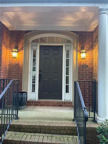 Brick exterior with a covered entry, dark paneled door, arched transom, and side light windows
