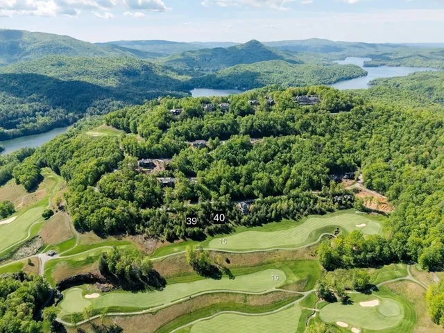 Aerial landscape showcasing a golf course, expansive bodies of water, and surrounding green mountains