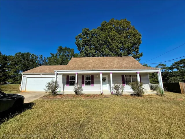 Ranch-style home with a shingled roof, a front yard, covered porch, concrete driveway, and an attached garage