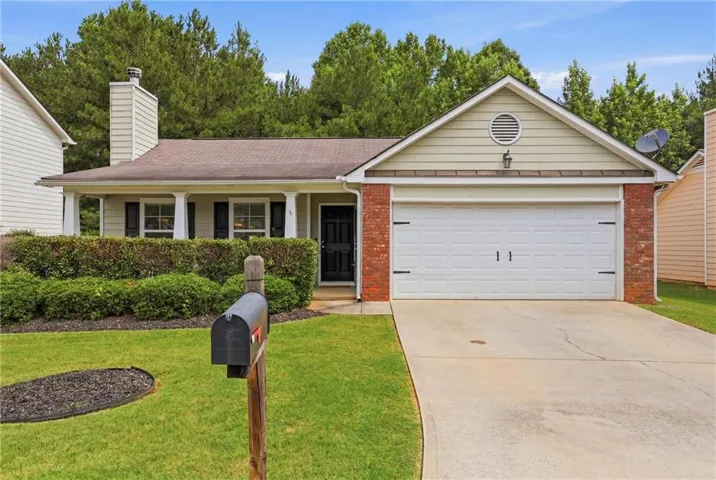 Brick and siding exterior with an attached garage, covered front porch, and manicured landscaping