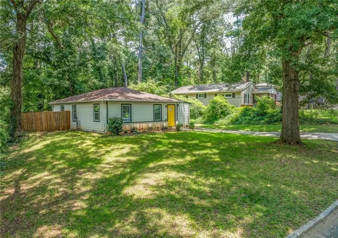 Expansive front lawn with mature trees and a paved driveway