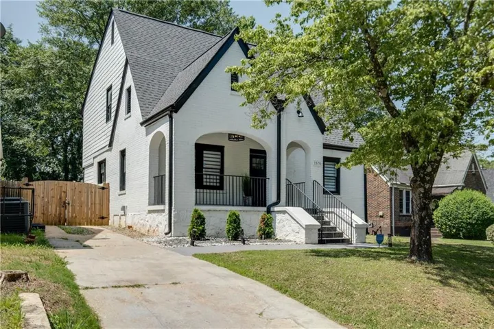 Charming white exterior with modern architectural details featuring a peaked roofline, arched entryway, and black-trimmed windows