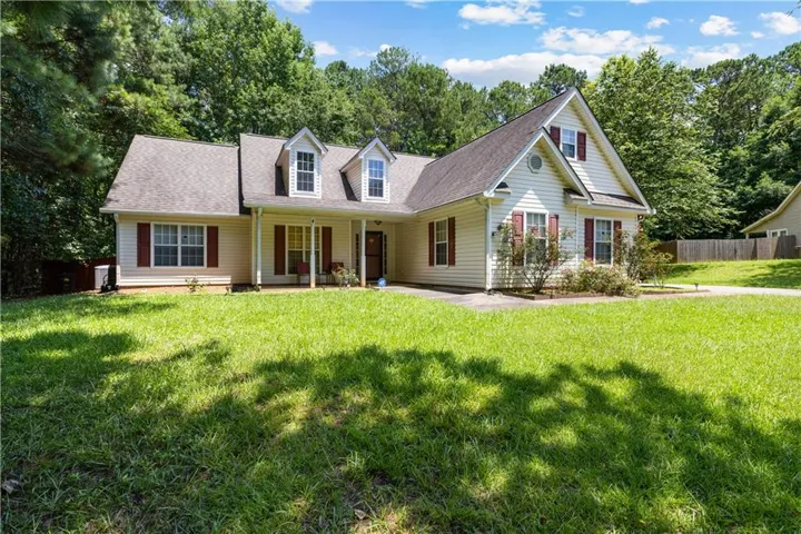 Cream-colored siding exterior with dark red shutters, a prominent front porch, and a dormer window feature
