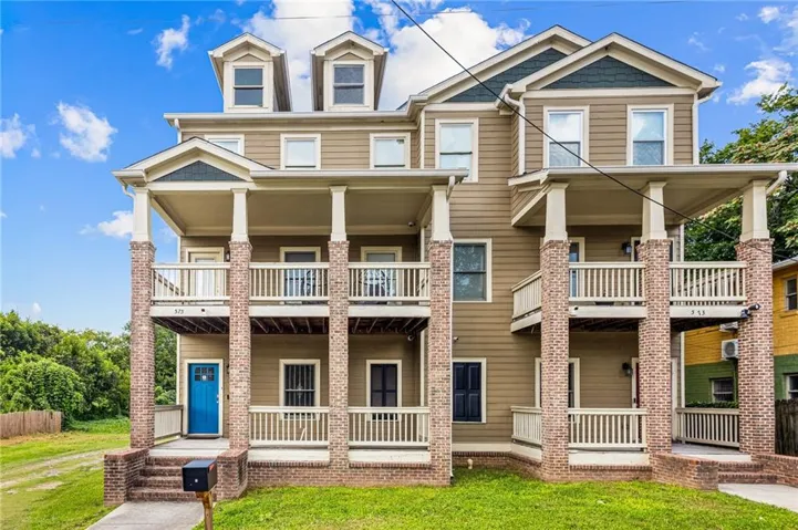 Multi-story facade featuring dormer windows and dual-level covered porches