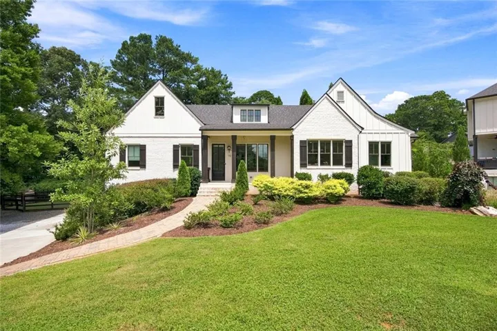 White brick exterior with dark shutters, gabled rooflines, and a covered entry