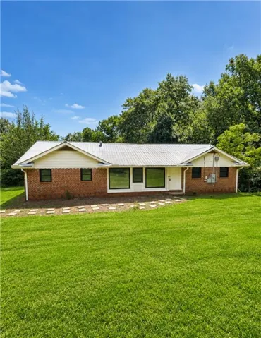 Brick exterior with white siding accents and a metal roof