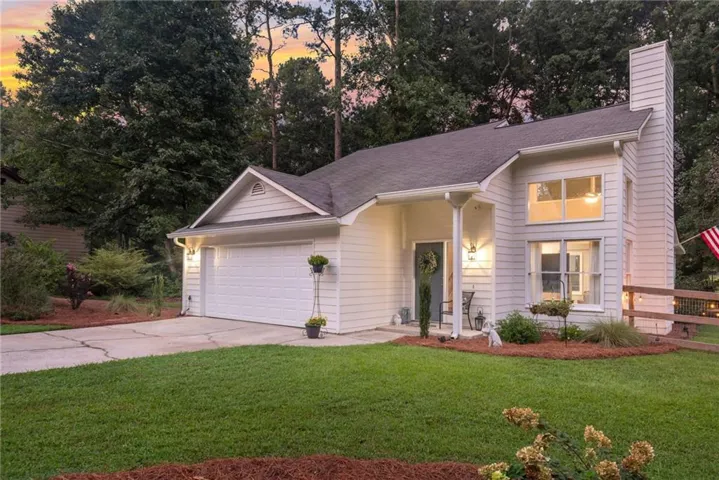 Siding exterior with a covered entry, attached two-car garage, and a prominent chimney