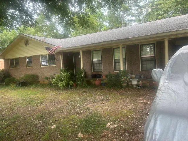 Brick exterior with a covered porch, multiple windows, and a gabled roofline