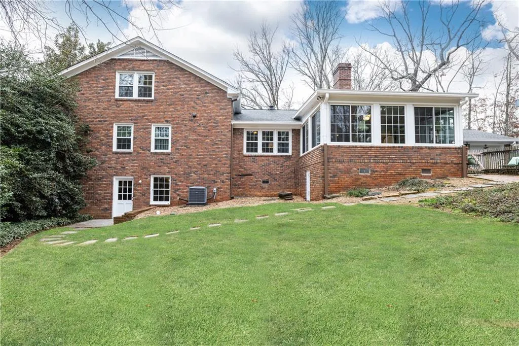 Back of property featuring brick siding, a yard, crawl space, and a chimney
