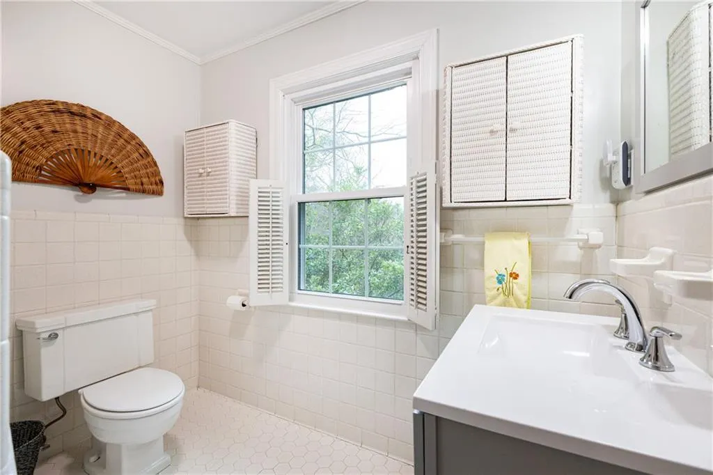 Bathroom with tile walls, a wainscoted wall, vanity, ornamental molding, and light tile patterned flooring