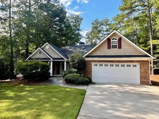 Brick and shingle exterior with a gabled roofline, arched window, and attached two-car garage