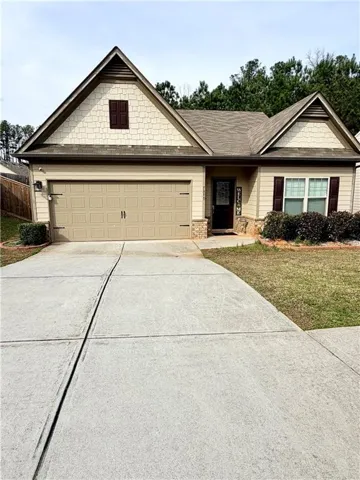 Craftsman-style home featuring a two-car garage, partial stone facade, and decorative window shutters