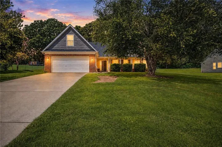 Brick and siding exterior with an attached garage, paved driveway, and established front landscaping