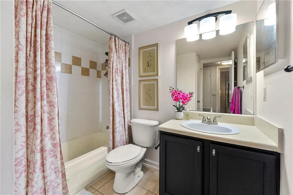 Bathroom with shower / bath combination with curtain, tile patterned floors, vanity, and a textured ceiling