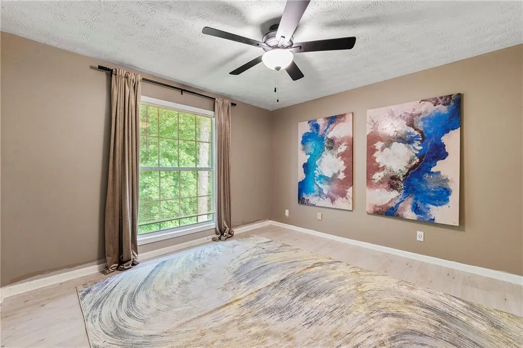 Unfurnished room with a textured ceiling, wood finished floors, and a ceiling fan