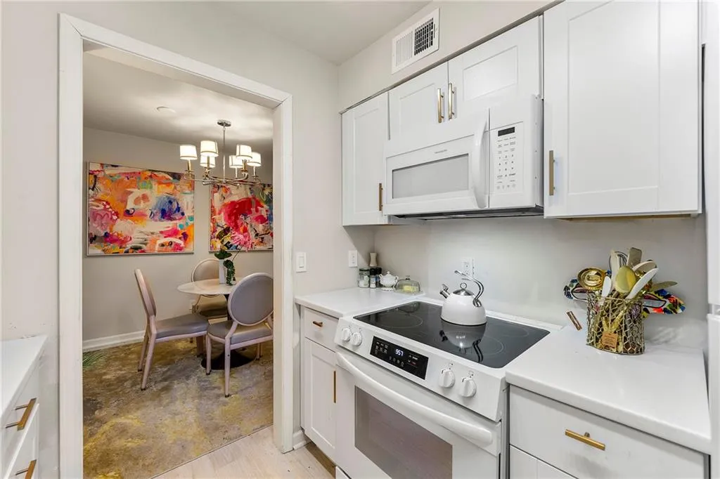 Kitchen featuring white appliances, white cabinetry, a chandelier, light countertops, and light wood finished floors