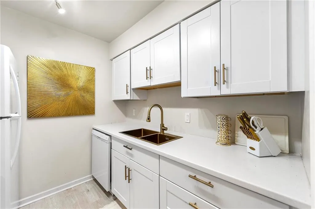 Kitchen with light countertops, light wood-style flooring, white appliances, and white cabinets