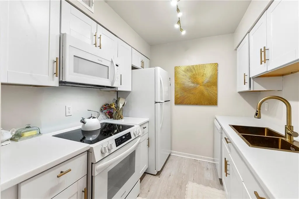Kitchen featuring white appliances, light wood-type flooring, and white cabinets