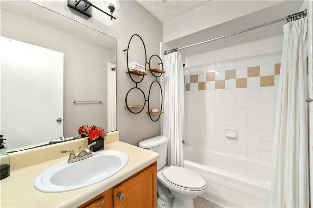 Bathroom featuring shower / tub combo, vanity, and a textured ceiling
