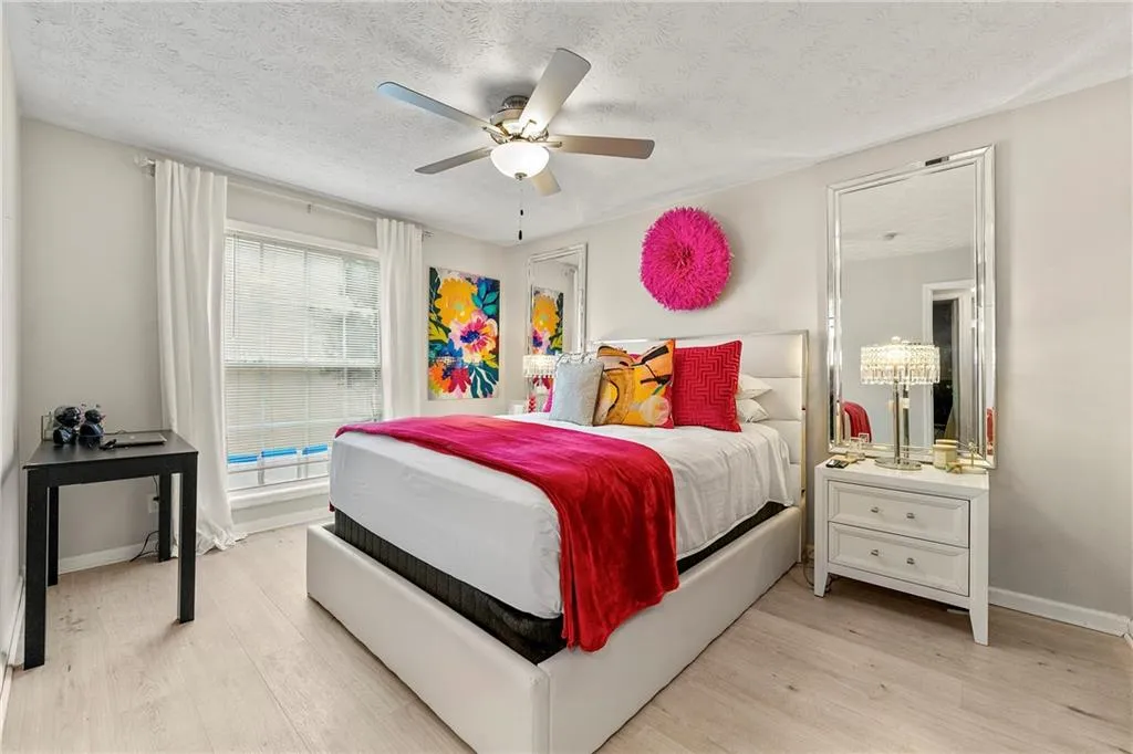 Bedroom featuring a textured ceiling, light wood-style floors, and a ceiling fan