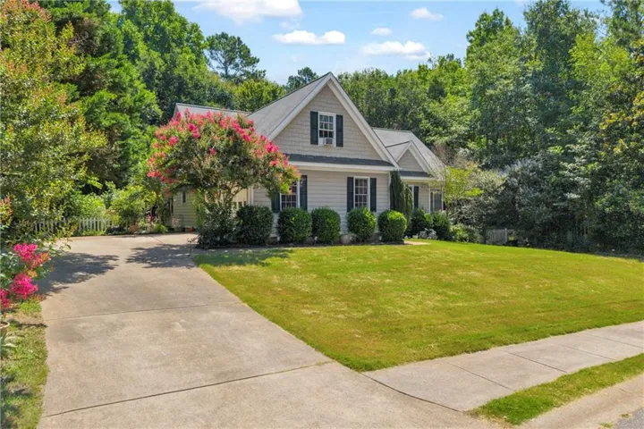Single-story home featuring light-colored siding, dark window shutters, and a front gabled dormer