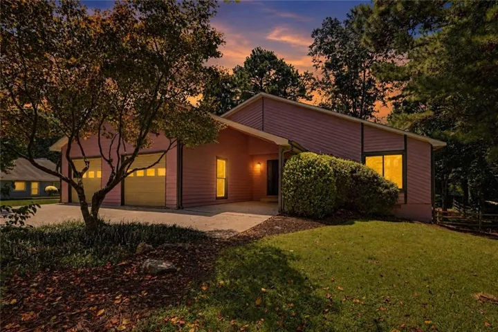Modern residential home featuring a dark metal exterior with horizontal siding, expansive glazing with illuminated interior spaces, and a welcoming front entrance